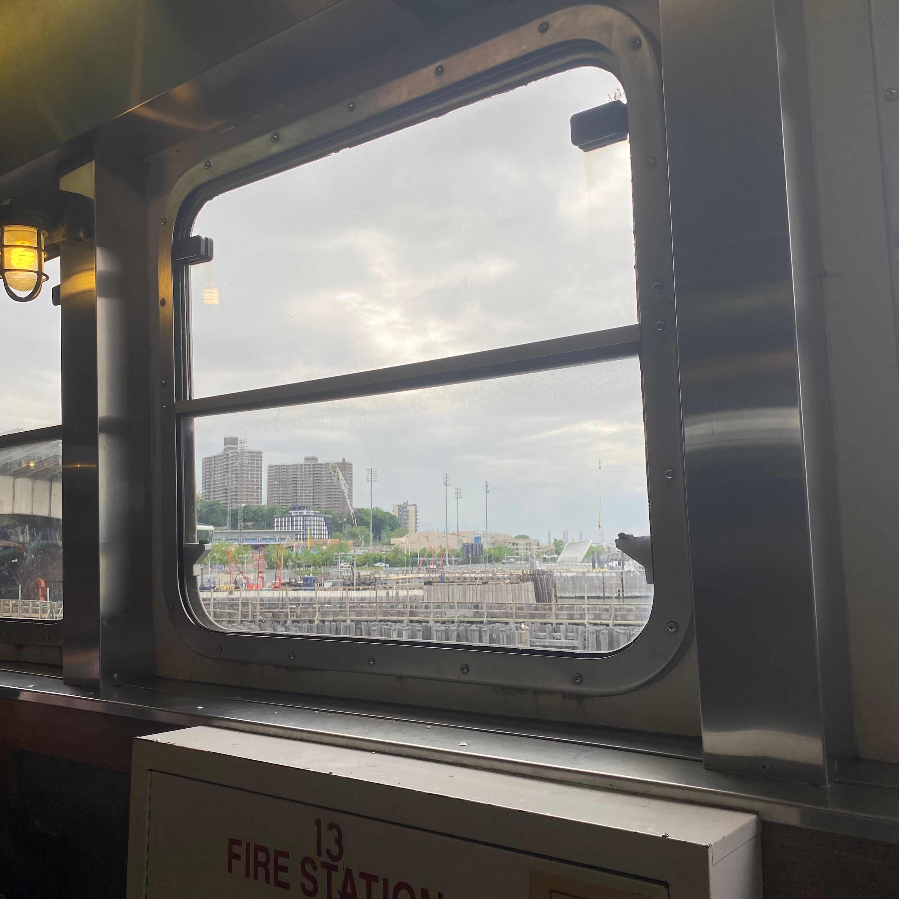 A ferry window with a view an overcast sky and two large apartment buildings.