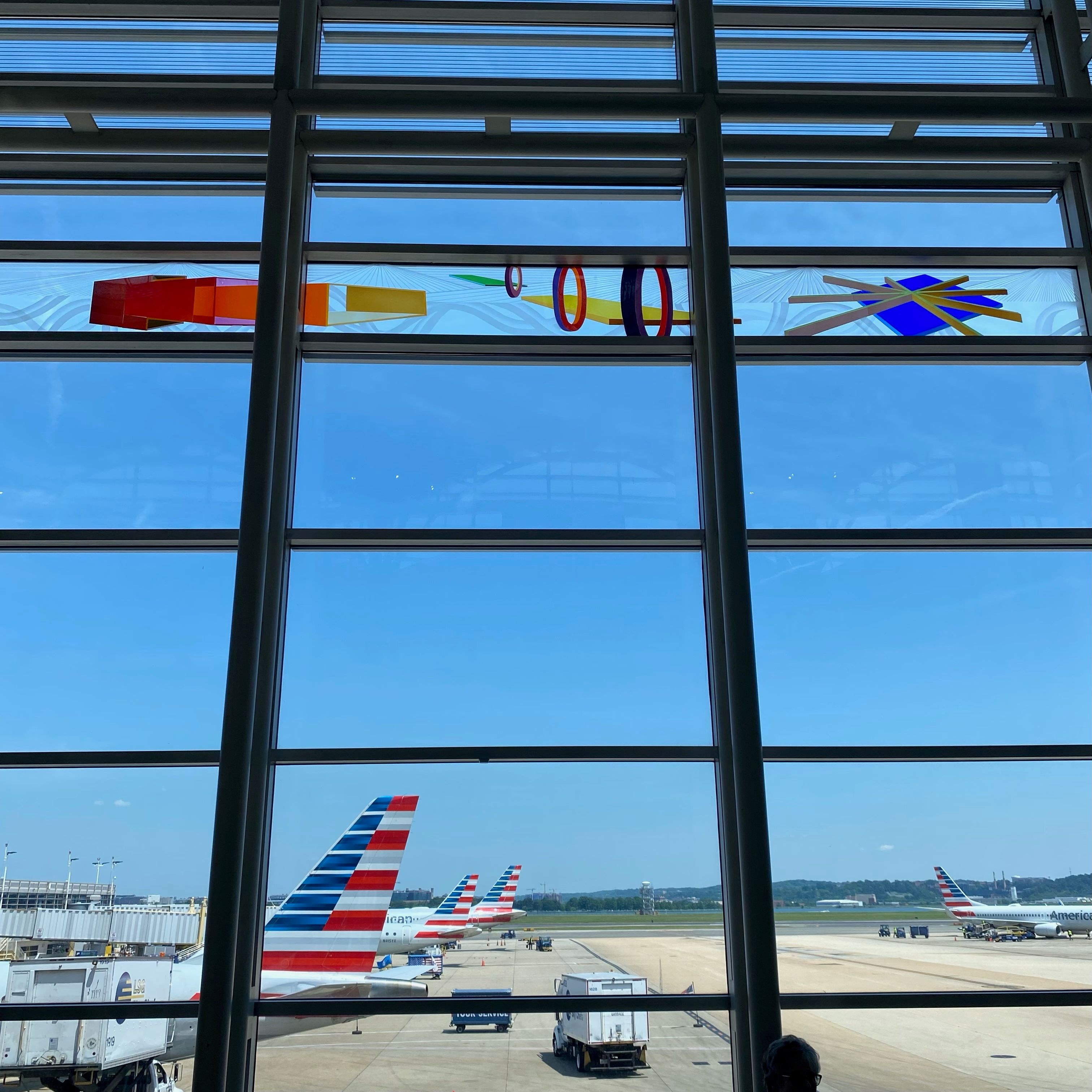 A grid of windows with a view of several airplanes. The planes have American flag decals on their tails.