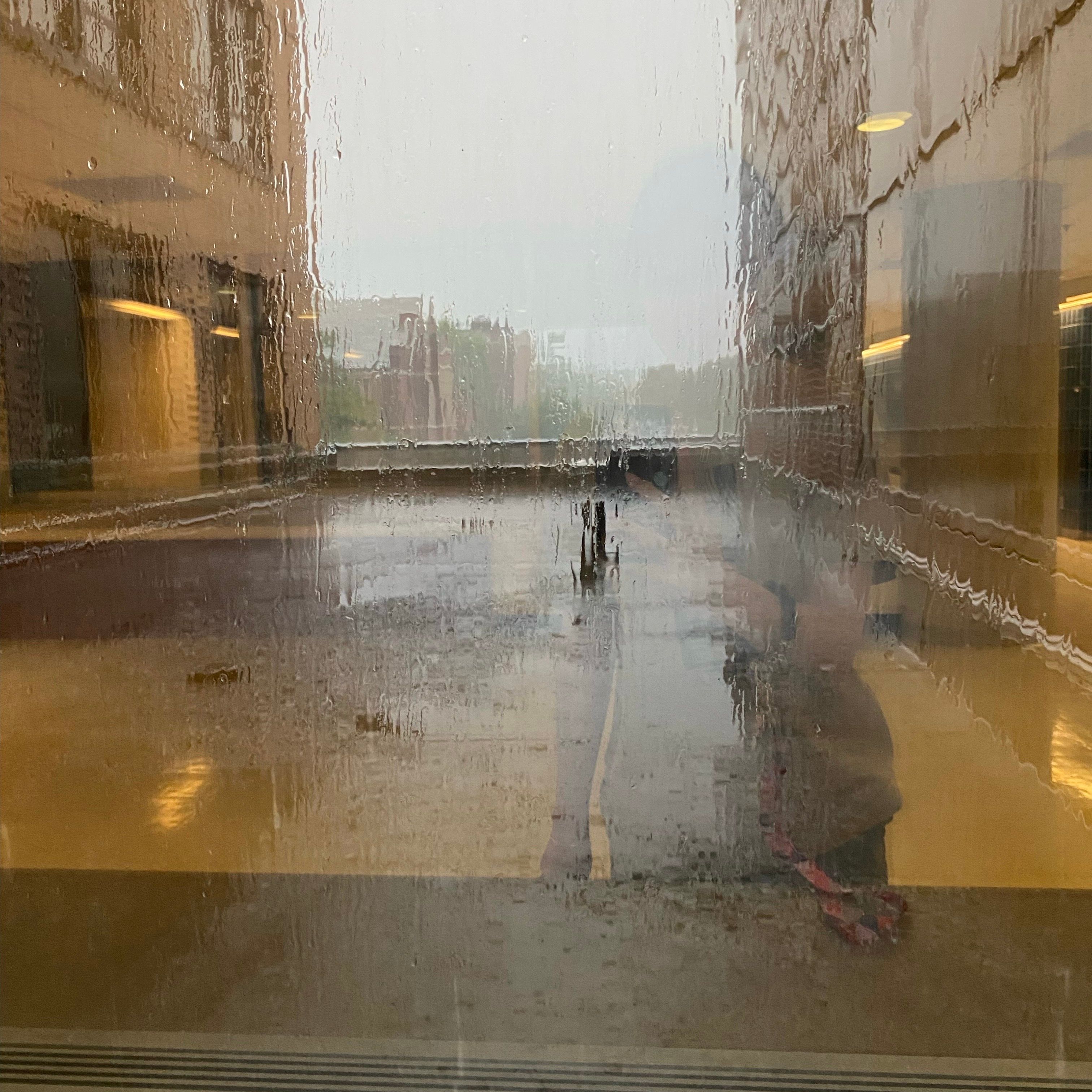 A window covered in rain with a view of a courtyard area.