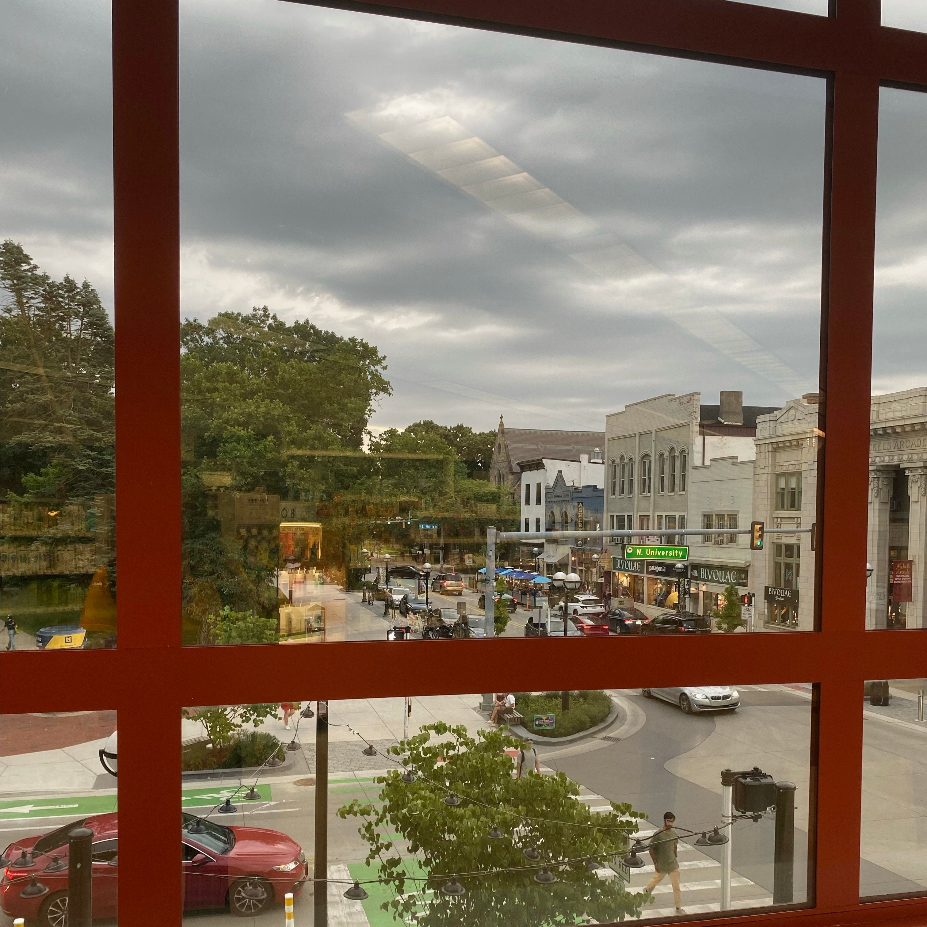 A window with a red frame. The window has a view of downtown Ann Arbor.