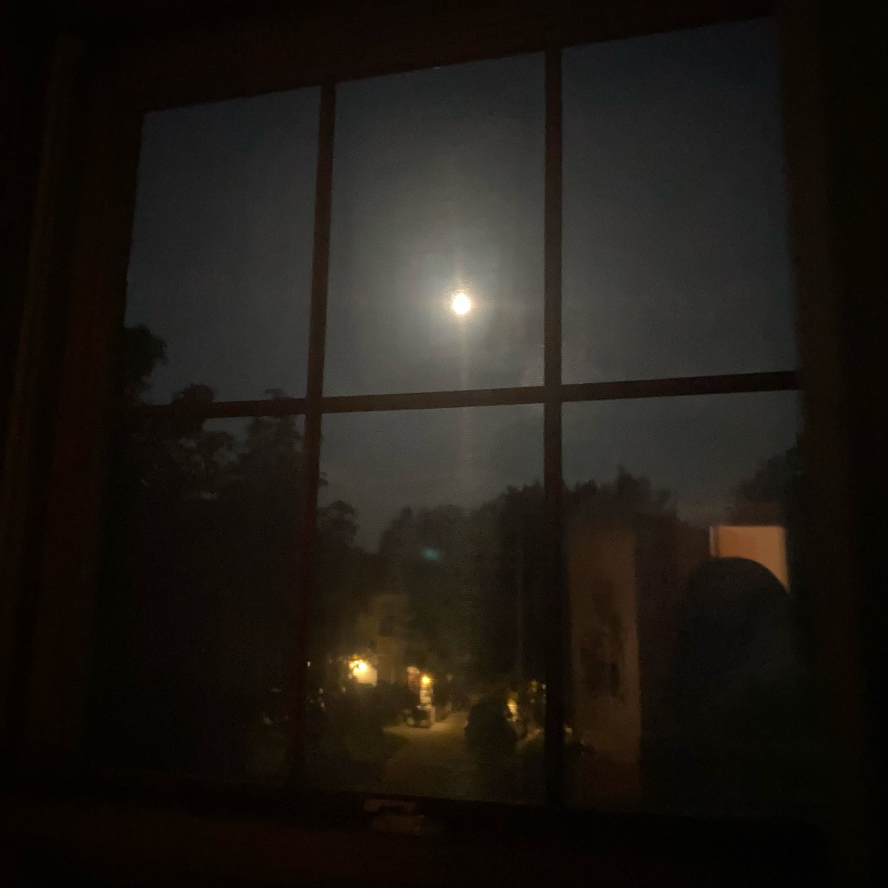 A window with a view of the moon in a dark sky.