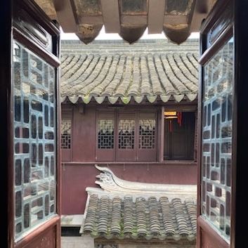 An open window with a view of a building with a historical East Asian style.