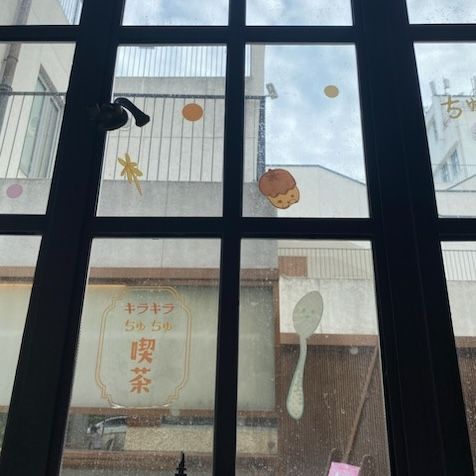 A window with a black frame and stickers on it. The stickers include a spoon, acorn and two circles.