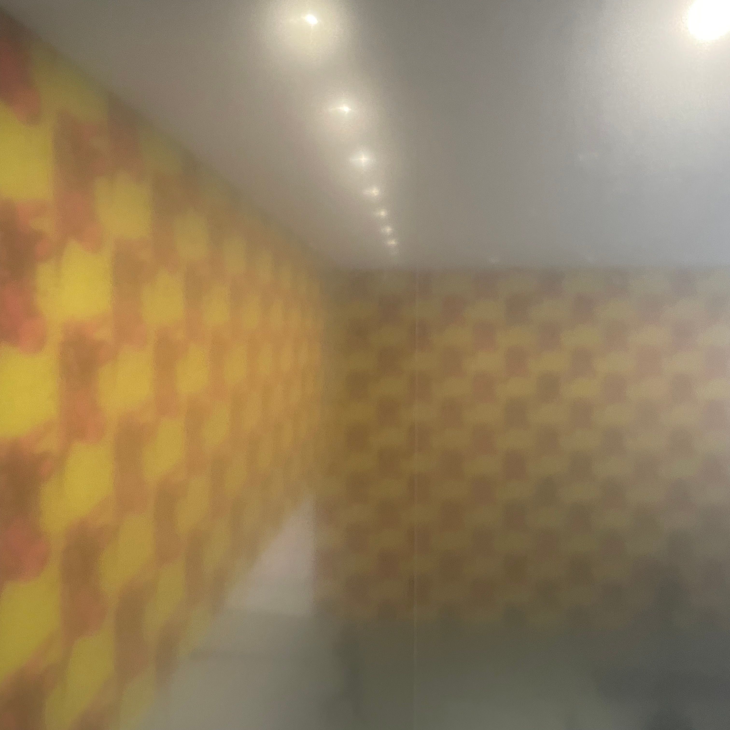 Blurry checkered yellow and pink pattern on two walls. The pink shapes are cow heads.