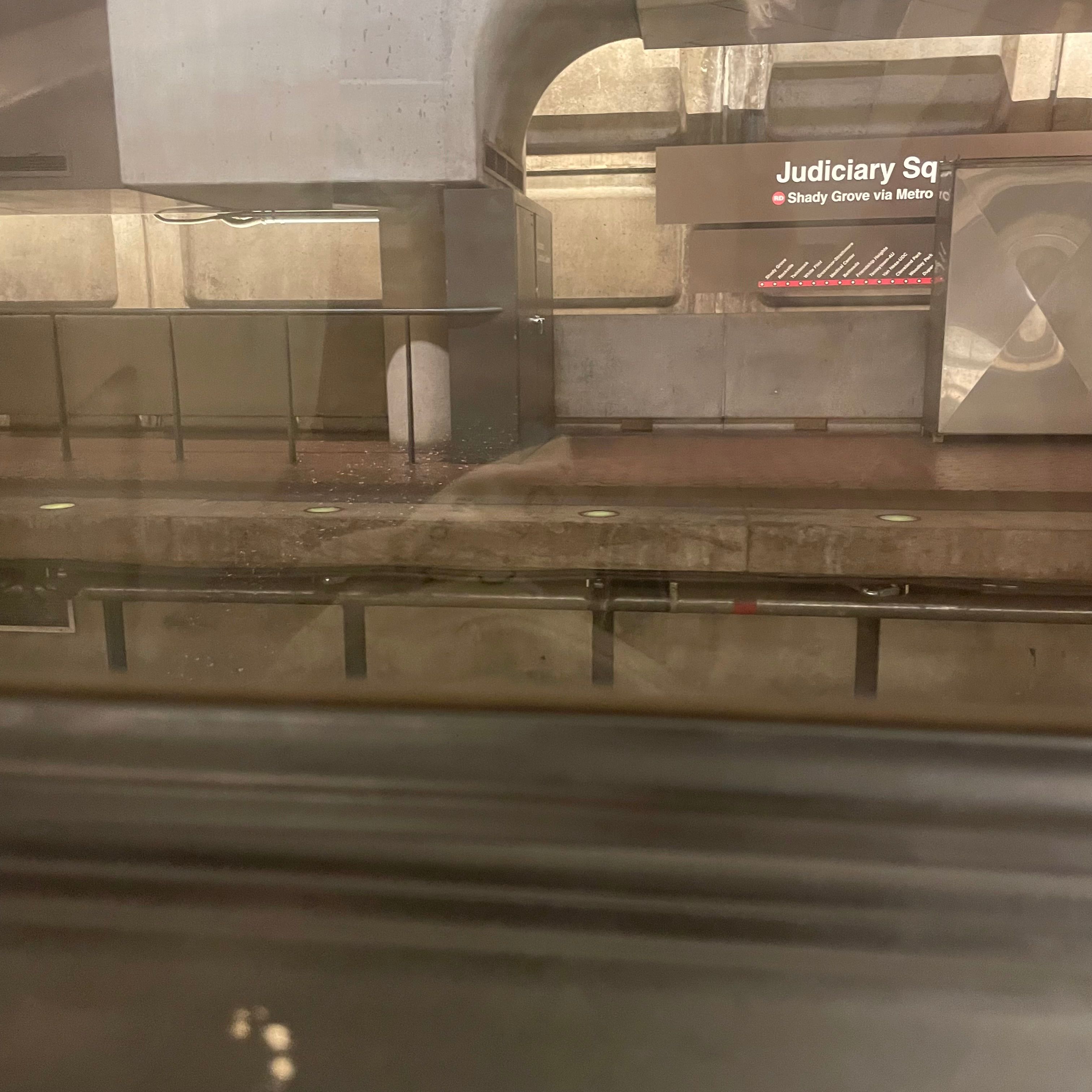 A train window with a view of the Judiciary Square Metro station.