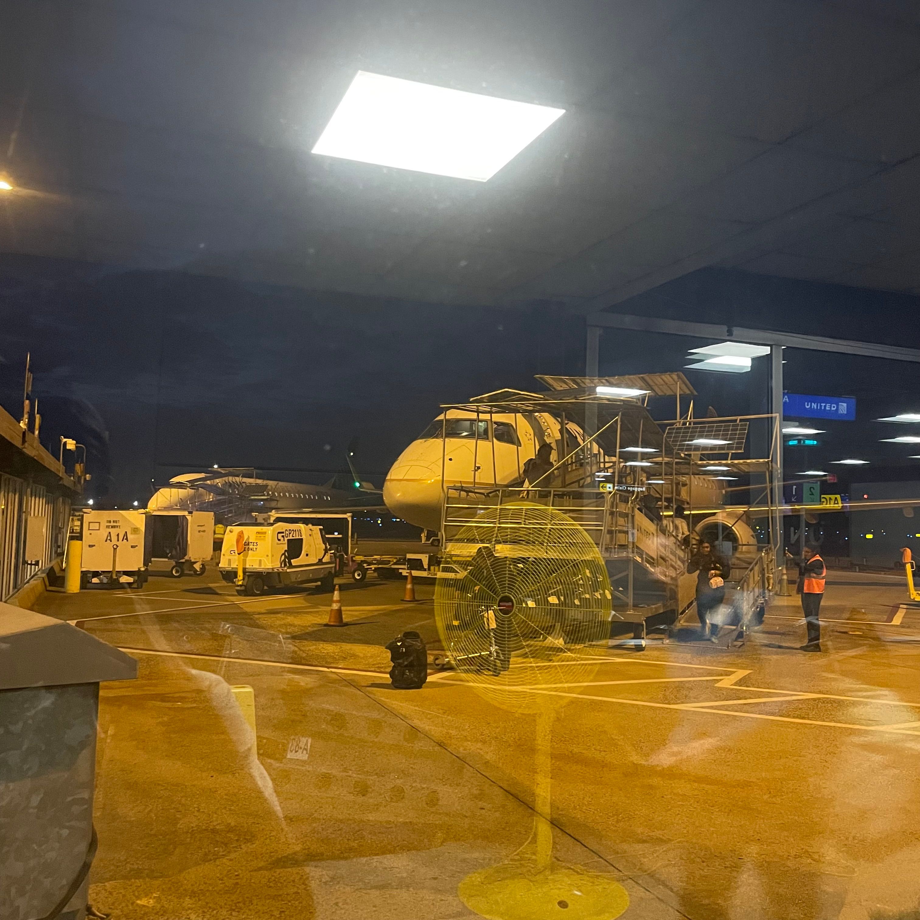 Window with a view of an airplane with a ramp attached.